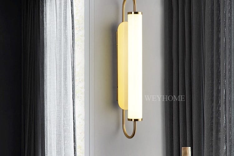 Modern minimalist gold led wall lamp featuring a sleek cylindrical frosted glass shade and curved metal frame ideal for bedroom use.