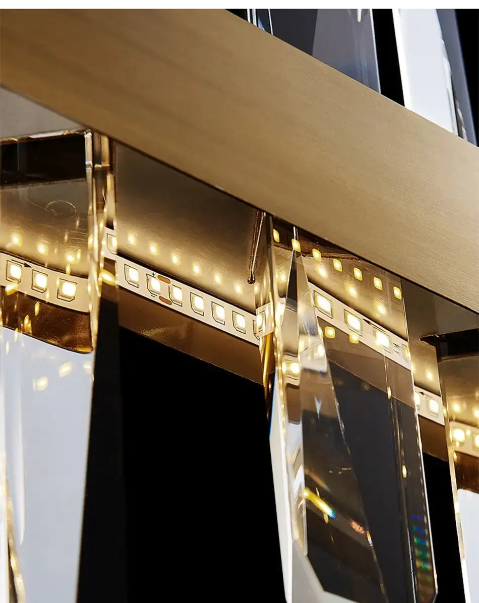 modern rectangle gold crystal chandelier with metal arms and faceted prisms reflecting warm led lights for dining room use