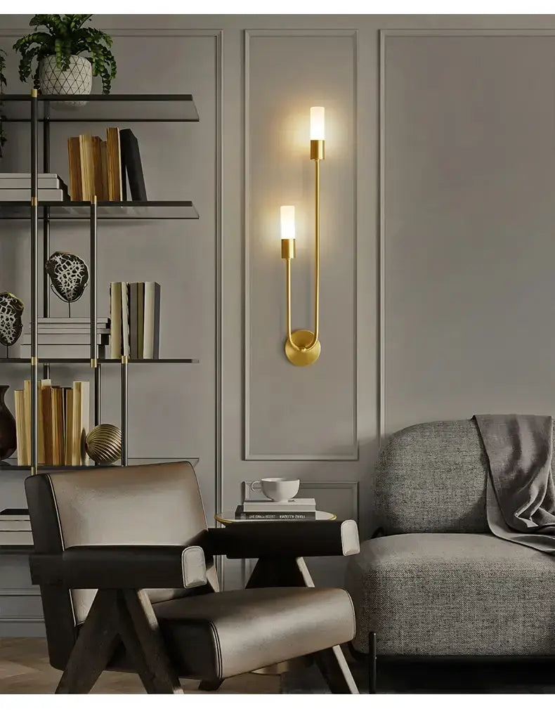 Modern gold-toned minimalist led wall lamp featuring two vertical candle-style lights with a sleek curved design for bedroom use.