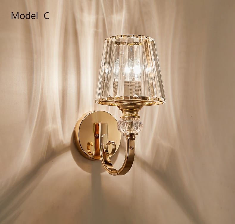 Modern minimalist gold wall lamp featuring a gold-finished wall sconce with a faceted crystal shade and decorative crystal accent for bedroom use.