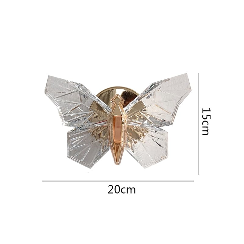 A clear geometrically faceted butterfly wall lamp with a gold-toned metallic body designed for luxury bedroom lighting.
