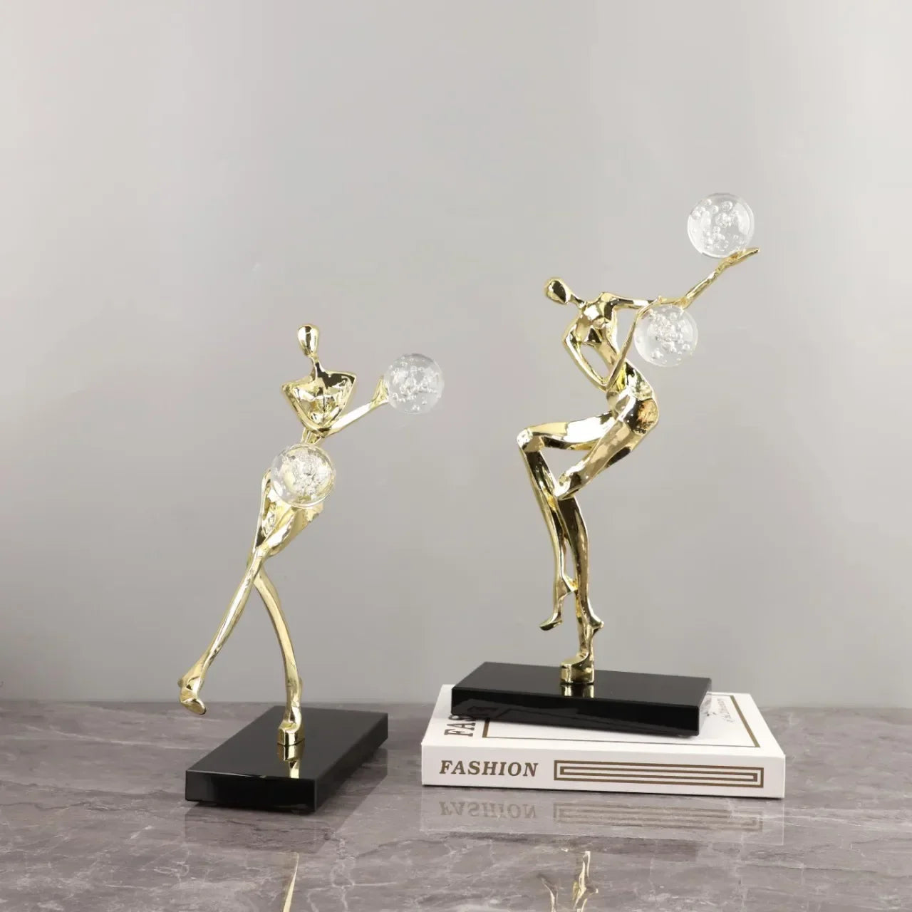 Figura escultórica acrobática de un hombre dorado bailando sobre una bola de cristal DecorBites™ para decoración del hogar
