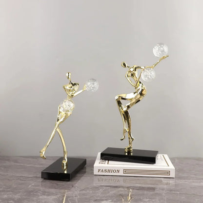 Figura escultórica acrobática de un hombre dorado bailando sobre una bola de cristal DecorBites™ para decoración del hogar