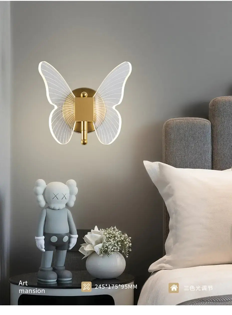 art deco gold-toned butterfly-shaped wall lamp with translucent white wings and a central circular light fixture designed for bedroom bedside wall use.