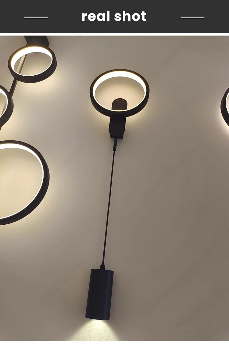 modern nordic led black gold wall lamp featuring a black circular wall sconce with a cylindrical pendant emitting warm light for bedroom use.