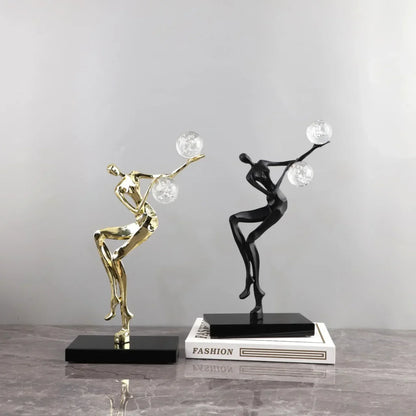 Figura escultórica acrobática de un hombre dorado bailando sobre una bola de cristal DecorBites™ para decoración del hogar