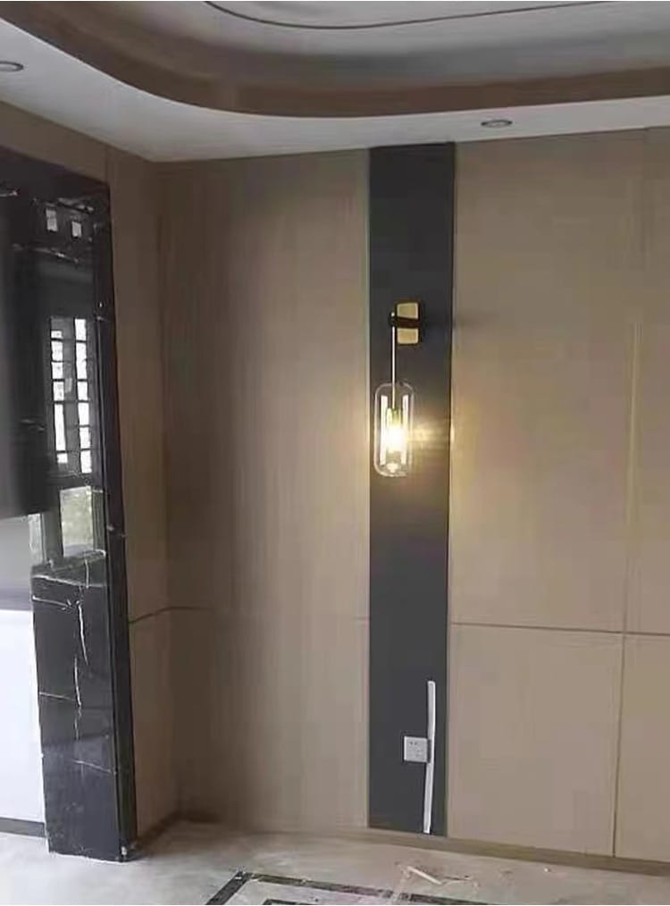 A modern wall-mounted sconce with a clear glass lampshade and brass-colored metal fixture designed for nordic modern decor in bedroom settings.