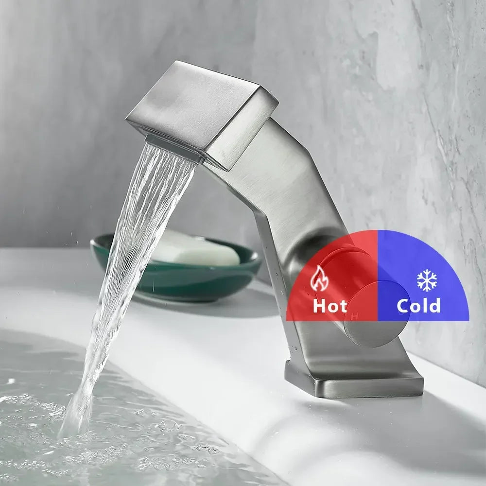 Modern brushed stainless steel waterfall faucet with a sleek angular design and dual hot cold control knobs for single hole installation in an antique gold finish with anti-splash spout.