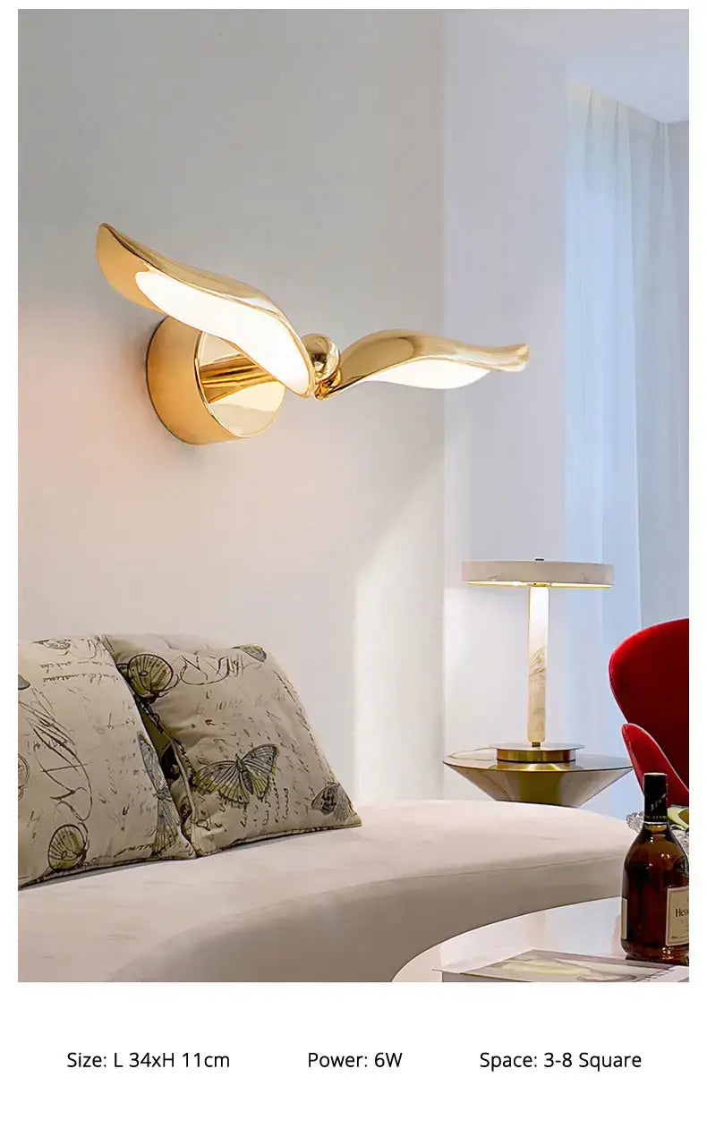 Gold-colored wall-mounted luxury minimalist creative seagull wall lamp with sleek metallic wings and integrated light source designed for bedroom and living room use.