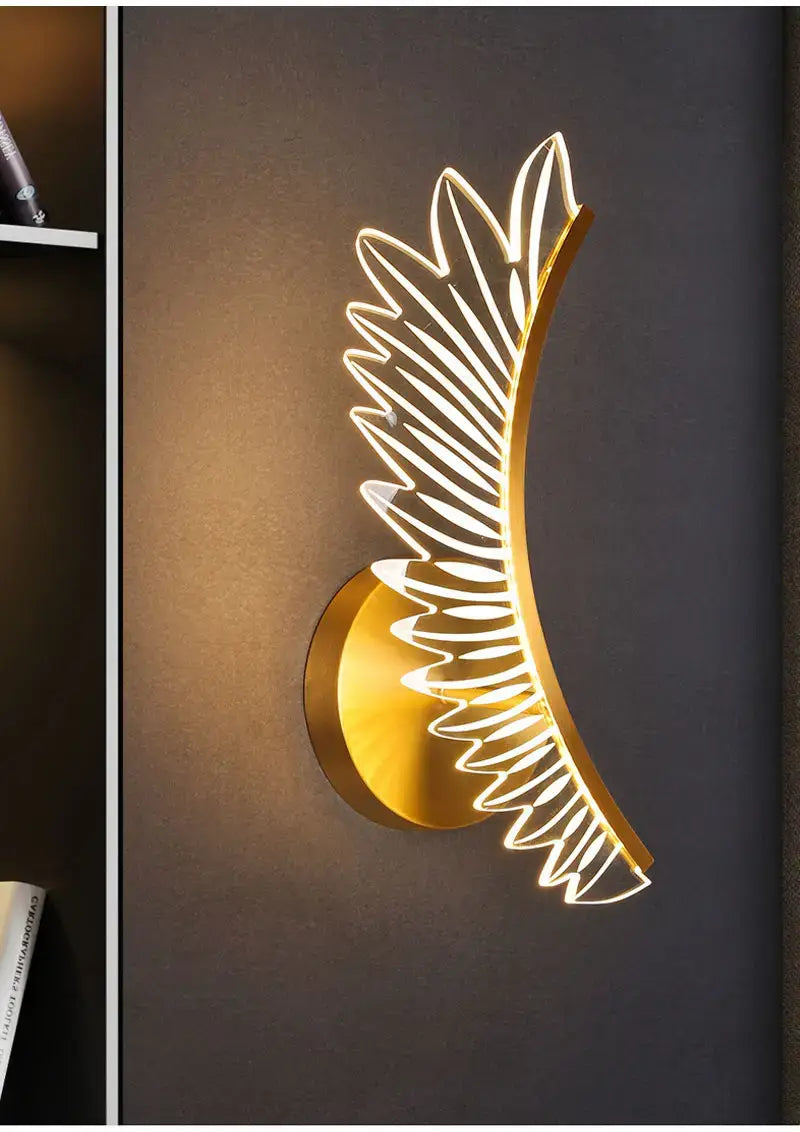 Golden wing-shaped wall lamp with illuminated led lighting in gold color designed as nordic modern art for modern art bedside use.