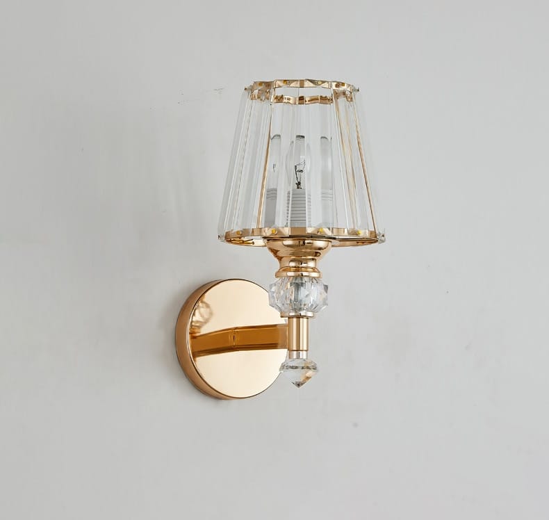 Modern minimalist gold wall lamp featuring a faceted crystal shade and decorative cut-glass elements for bedroom use.