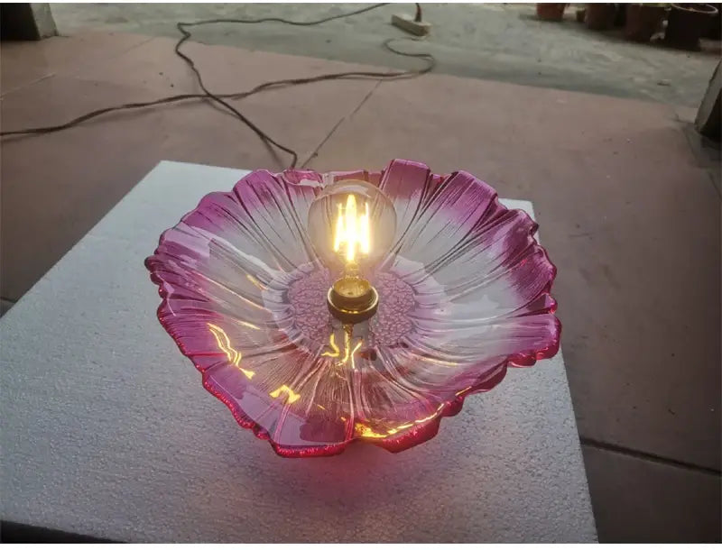 A translucent pink flower glass pendant light with a petal-like design and exposed filament bulb suitable for home decor and dining room use.
