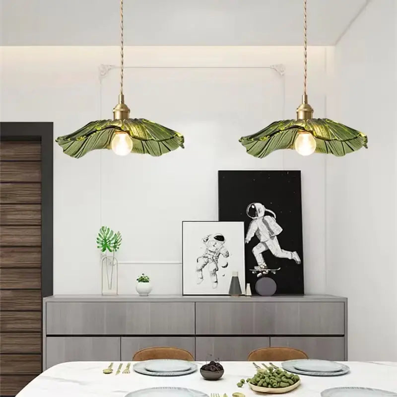 Green leaf-shaped pendant lights with brass fixtures featuring flower glass elements ideal for dining room home decor.
