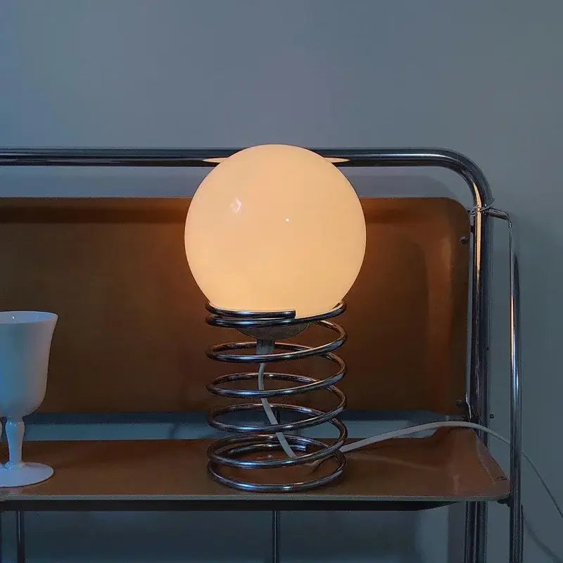 warm glowing white glass bauhaus spring table lamp with chrome spring base for bedroom lighting