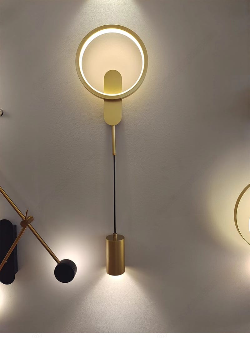 modern nordic led wall lamp featuring a gold-toned circular wall sconce with a black gold cylindrical pendant hanging below by a black cord, designed for bedroom use.