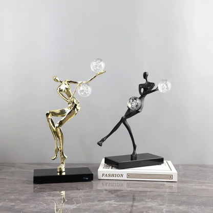 Figura escultórica acrobática de un hombre dorado bailando sobre una bola de cristal DecorBites™ para decoración del hogar