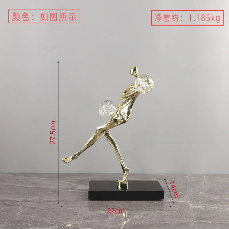 Figura escultórica acrobática de un hombre dorado bailando sobre una bola de cristal DecorBites™ para decoración del hogar