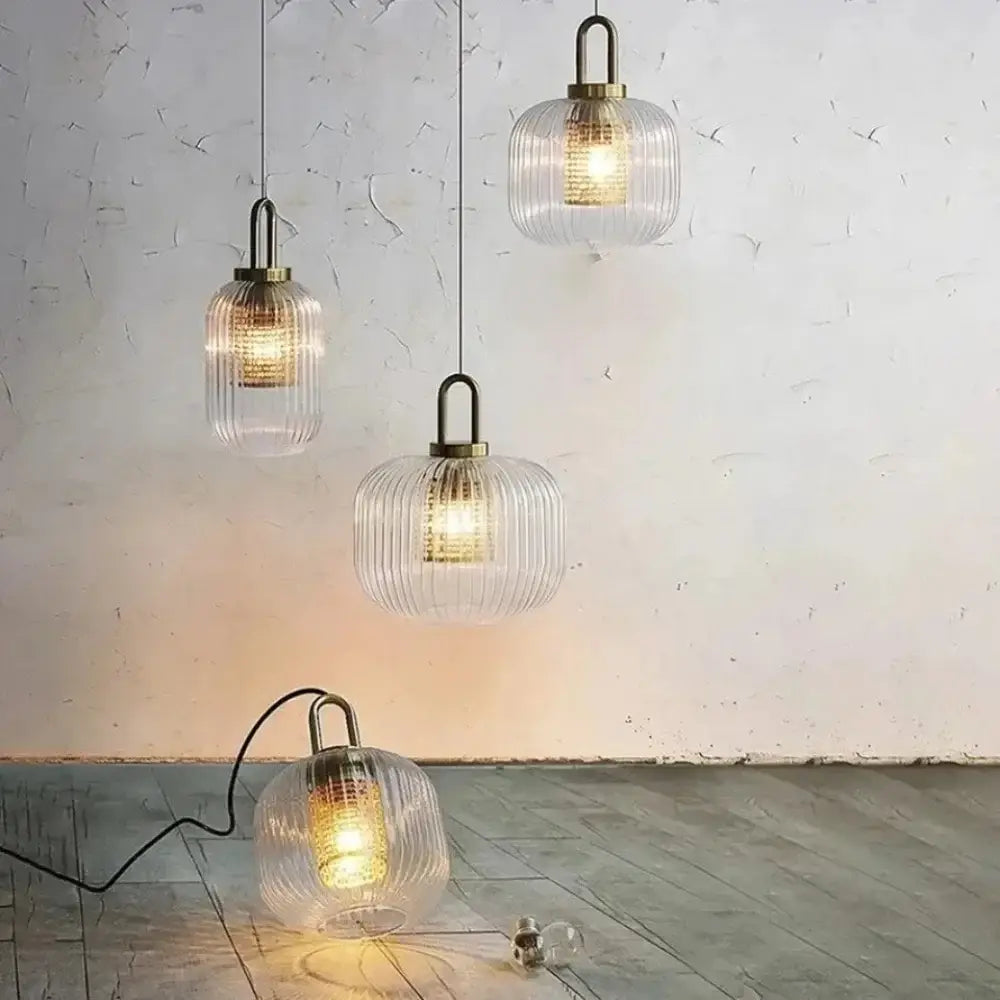 clear ribbed glass pendant lights with brass accents hang from the ceiling and one rests on the floor next to a vintage brass deer head wall lamp suitable for bedroom use