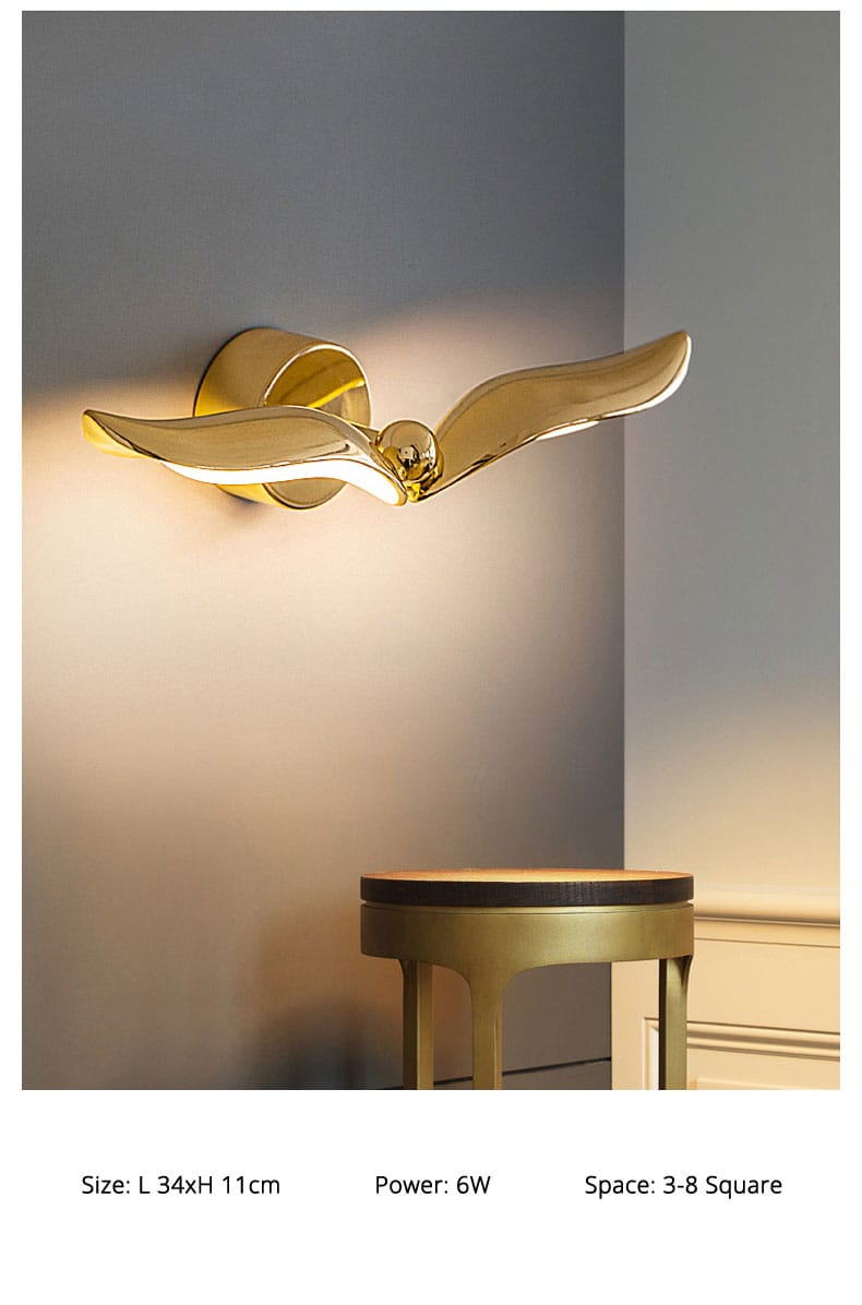 Luxury minimalist creative seagull wall lamp featuring a golden wing-shaped wall sconce with a sleek reflective finish and a central spherical accent for bedroom and living room.