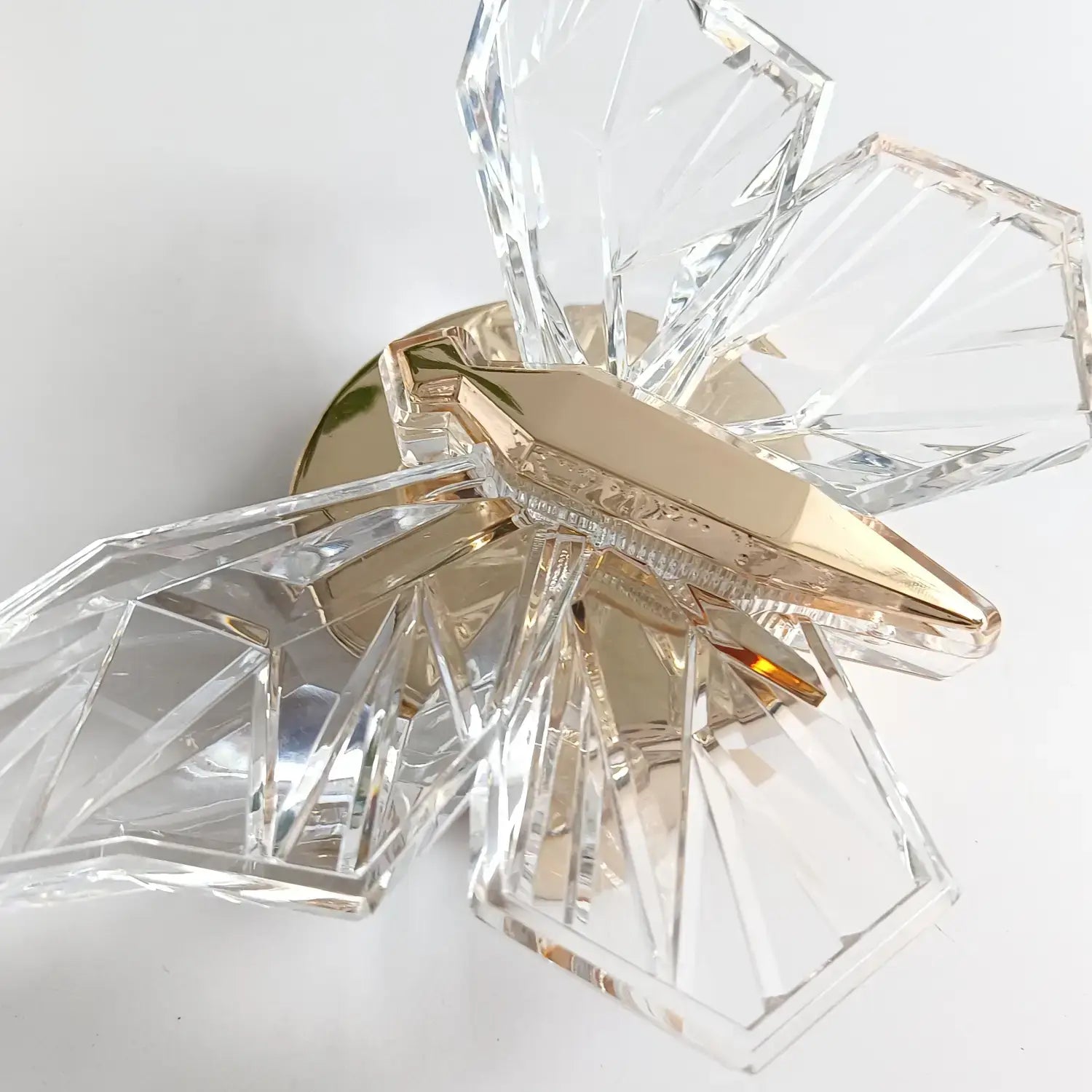 A luxury gold butterfly wall lamp featuring a modern crystal design with faceted clear glass wings and a polished gold-toned central body for bedroom lighting.