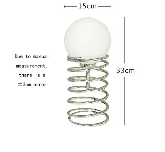 a sleek 33cm tall bauhaus spring table lamp with a chrome spring and smooth white glass spherical top designed as a bedroom light