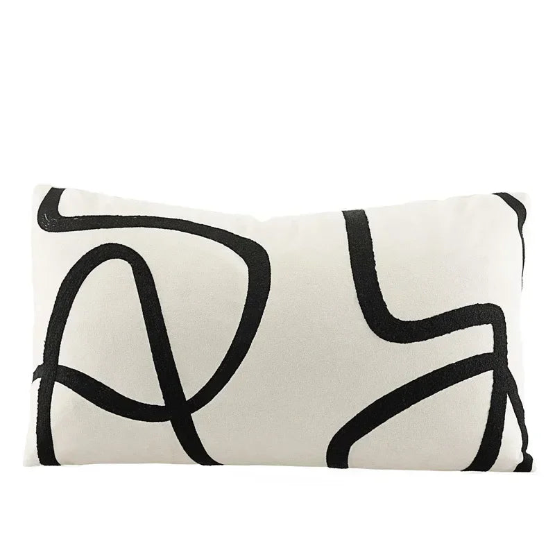 Funda de almohada bordada con líneas geométricas DecorBites™ en lona de ante negra, blanca y beige.