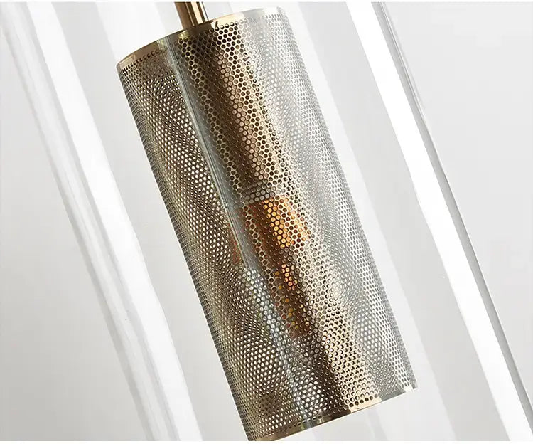 A nordic modern decor brass and glass wall lamp for bedroom featuring a cylindrical pendant light with a perforated brass mesh glass lampshade and sleek modern decor design.
