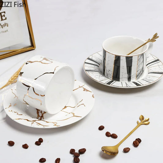 Juego de taza y platillo de cerámica con textura de mármol dorado DecorBites™ para té y café en la mesa.