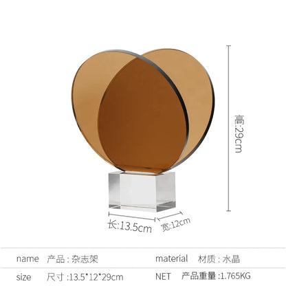 رف كتب ومجلات من ديكوربايتس™ مصنوع من الأكريليك والكريستال، مزين بزخارف هندسية دائرية، وتماثيل صغيرة من العنبر
