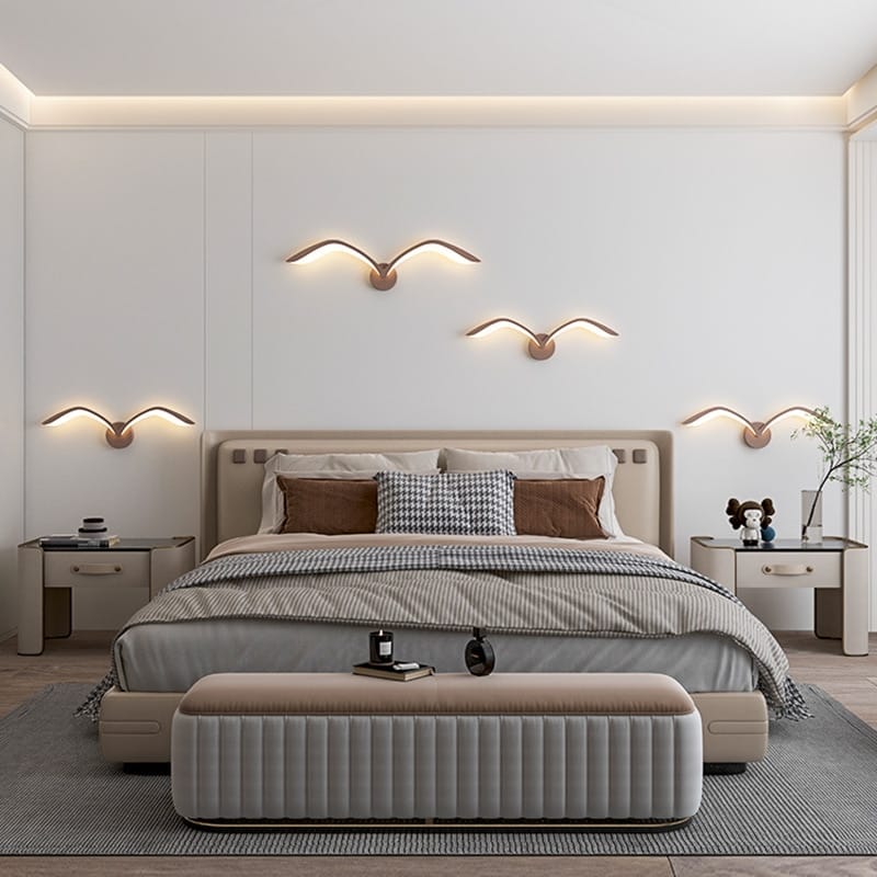 Modern beige upholstered bed with tufted headboard and matching footstool paired with a white nordic avian style wall lamp for style indoor bedroom lighting