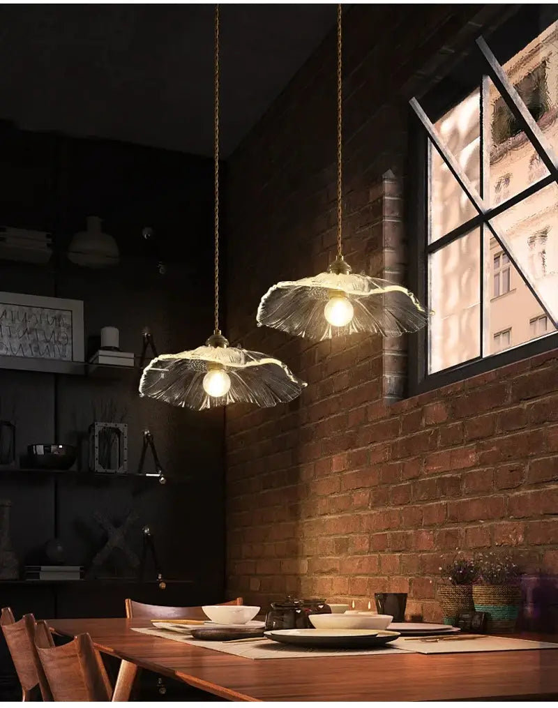 Two pendant lights with translucent leaf-shaped flower glass shades in vintage pink green and white colors featuring warm-toned bulbs ideal for dining room home decor.