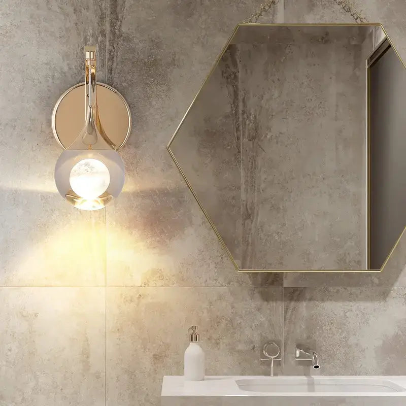 Modern luxurious crystal led wall sconce in gold with a curved lamp design featuring a spherical frosted glass shade and polished metal accents for bedroom use.