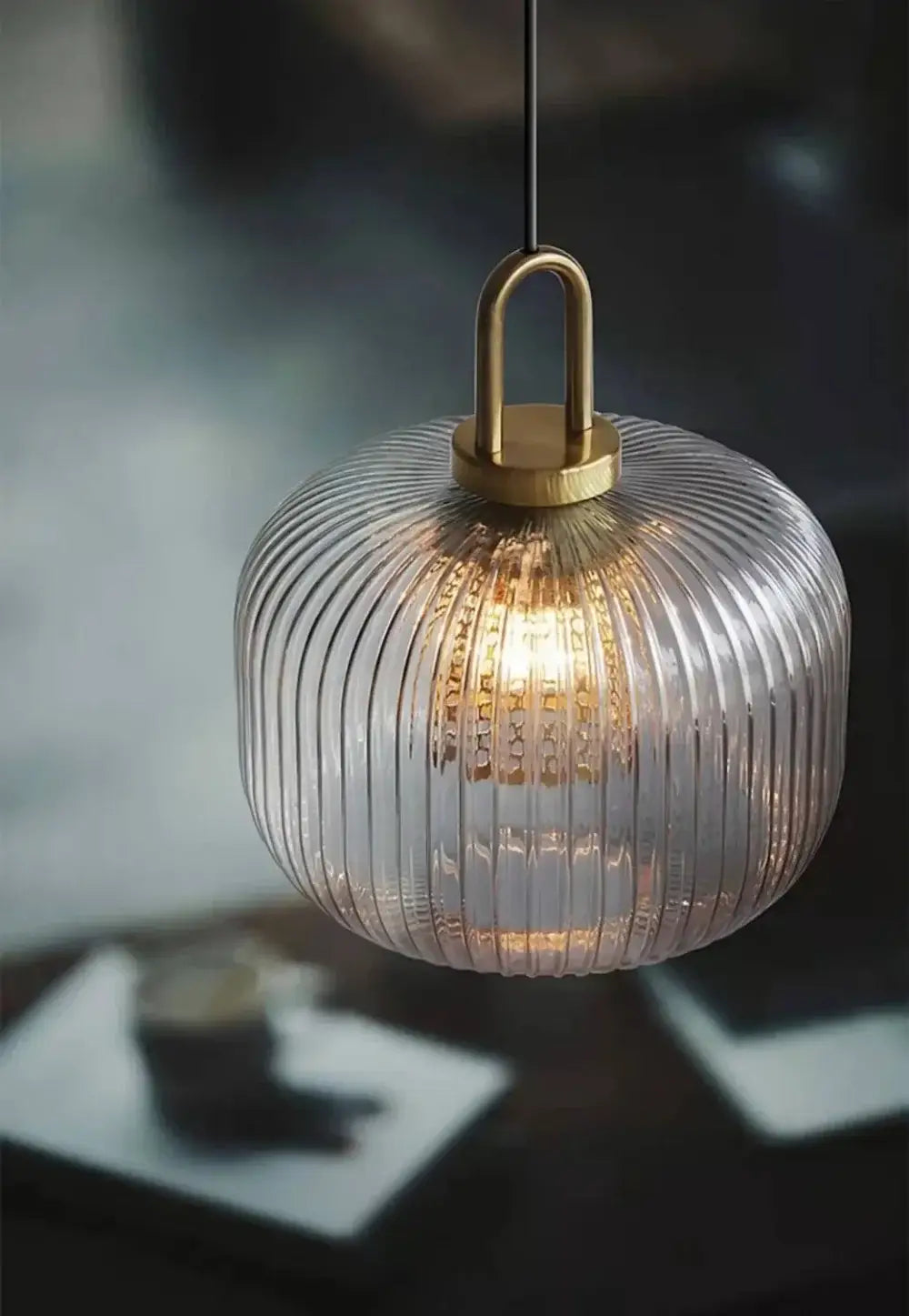 A vintage brass deer head wall lamp featuring a warm-glowing pendant light with a clear ribbed glass globe and brass-finished metal fixture.