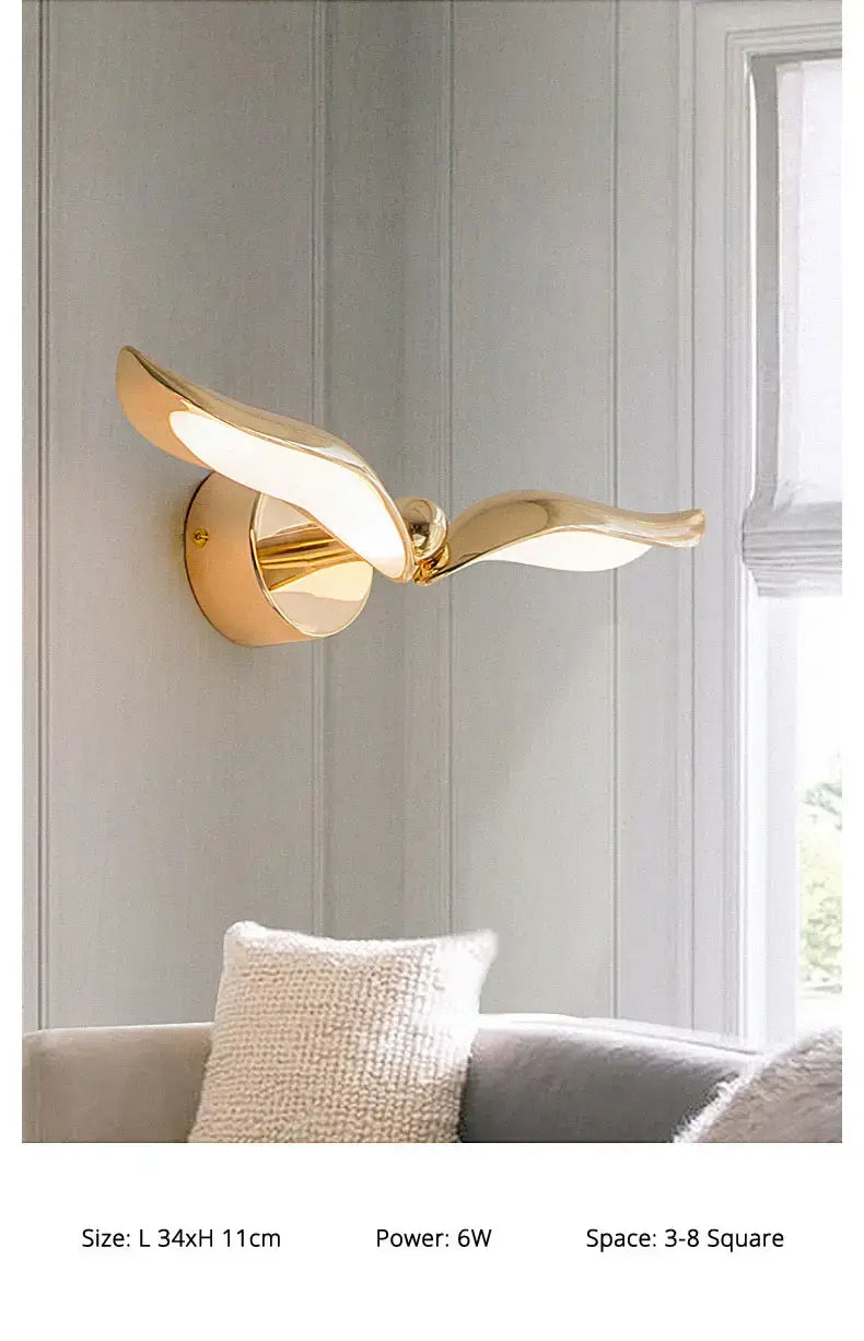 Gold-colored wall-mounted luxury minimalist creative seagull wall lamp with a sleek wing-like design and smooth metallic finish for bedroom and living room.