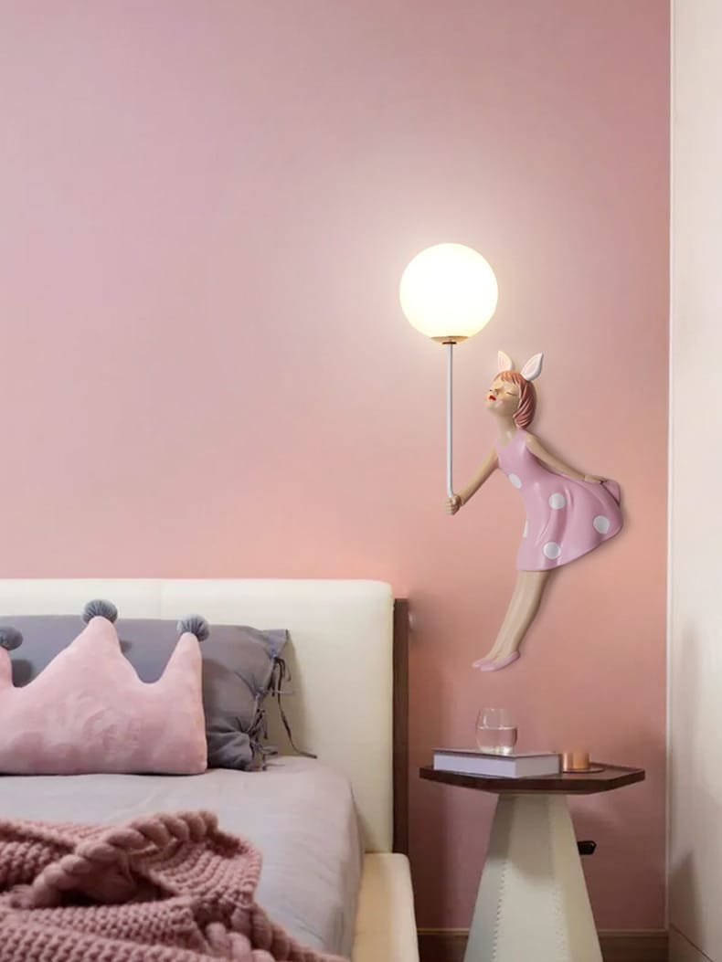 whimsical pink polka dot fairy girl wall lamp with bunny ears holding a glowing spherical light designed as a girl wall lamp for bedroom decor