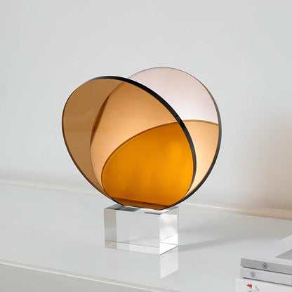 رف كتب ومجلات من ديكوربايتس™ مصنوع من الأكريليك والكريستال، مزين بزخارف هندسية دائرية، وتماثيل صغيرة من العنبر