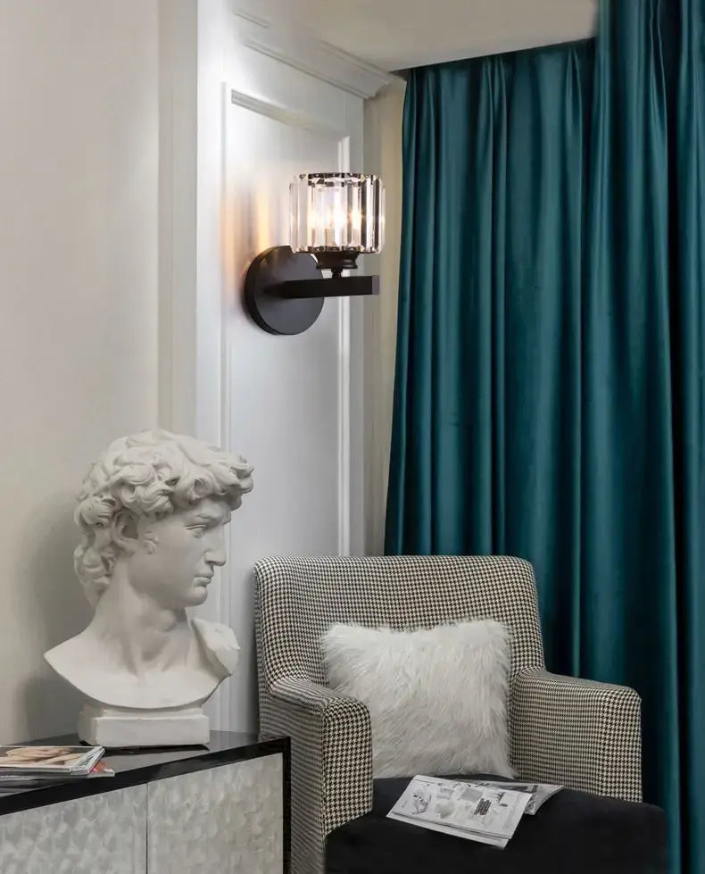 white marble bust of david with detailed curly hair displayed beside a modern minimalist gold wall lamp with crystal shade for bedroom lighting.
