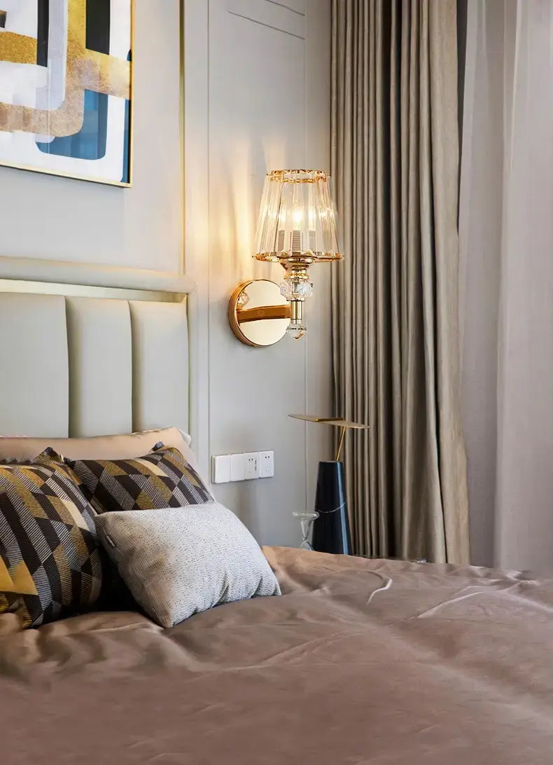 modern minimalist wall lamp featuring a gold-toned sconce with a crystal-encrusted base and a clear faceted glass shade, ideal for bedroom lighting.