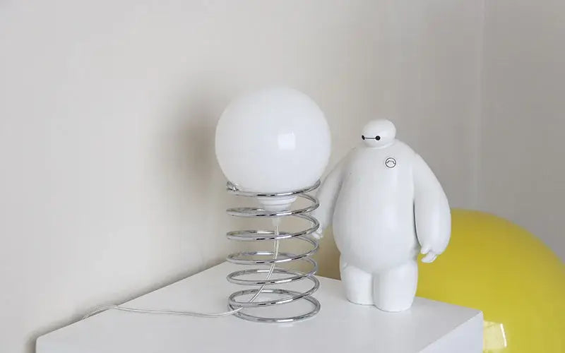 white spherical lamp with chrome spring base is an ins bauhaus spring table lamp made of white glass and chrome for bedroom lighting.