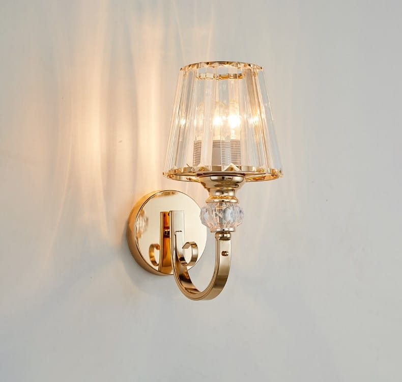 Modern minimalist gold wall lamp featuring a gold-toned wall sconce with a faceted crystal shade and decorative crystal bead for bedroom use.