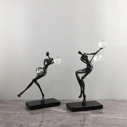 Figura escultórica acrobática de un hombre dorado bailando sobre una bola de cristal DecorBites™ para decoración del hogar