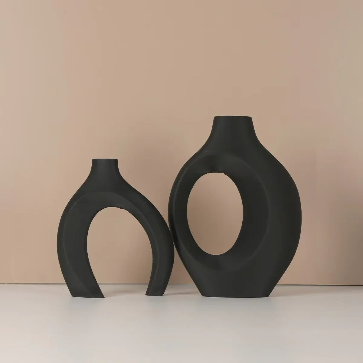 Two matte black ceramic vases with hollow oval cutouts for modern home decor made in mainland China