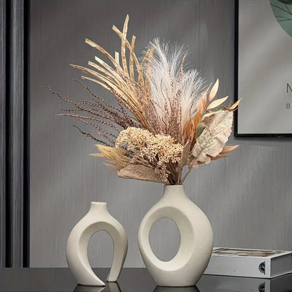 A modern white plastic imitation hollow vase set of 2 with circular cutouts holding dried grasses made in mainland china