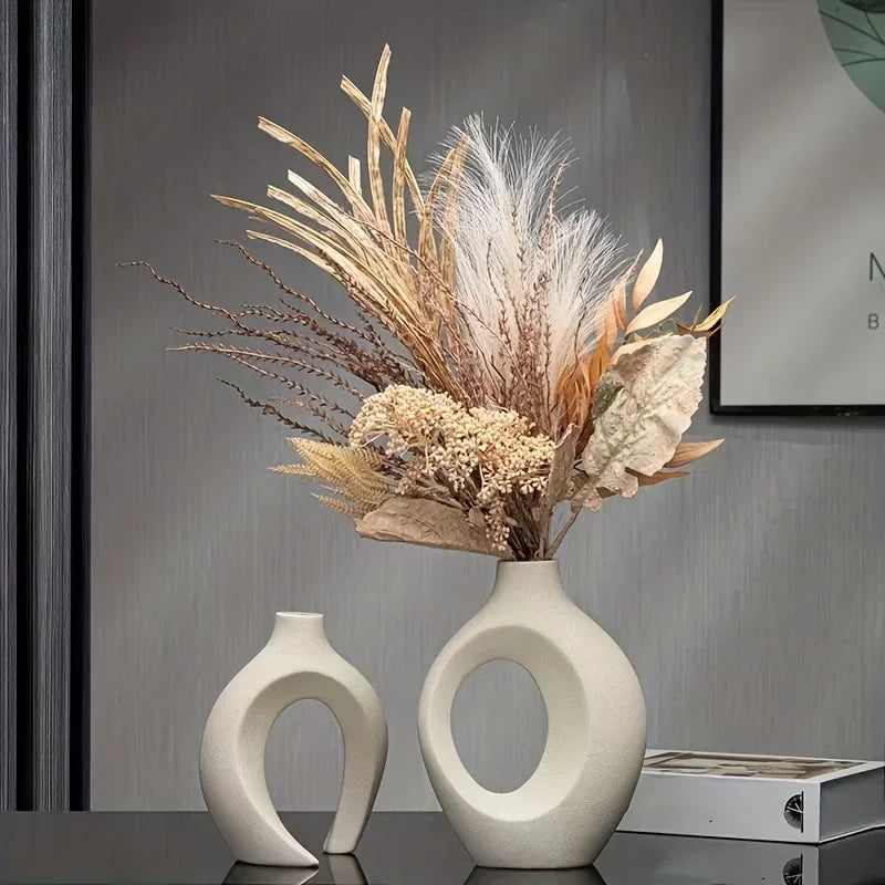 A modern white plastic imitation hollow vase set of 2 with circular cutouts holding dried grasses made in mainland china