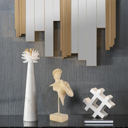 White marble vase with gold-tipped floral arrangement beside abstract beige david bust resin sculpture for living room decor