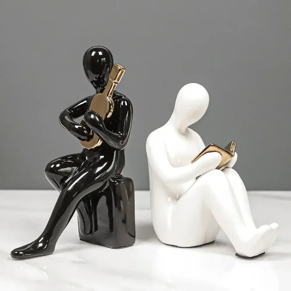 Black glossy ceramic character bookends in abstract nordic style featuring seated person playing guitar with gold accents