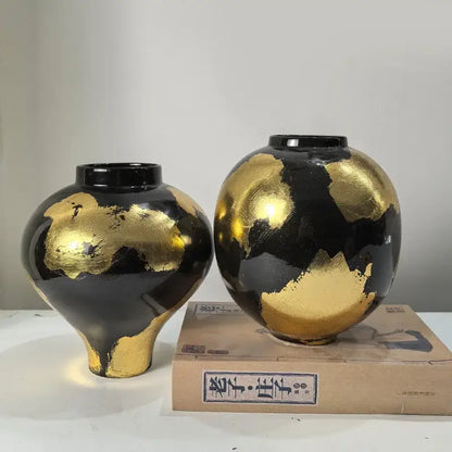 Two glossy black ceramic vases with abstract gold foil pattern in rounded and bulbous shapes for living room decor