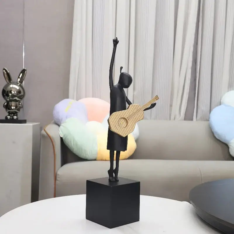 Abstract black and gold guitarist resin sculpture featuring a black resin dancer holding a woven gold guitar on a black cube base