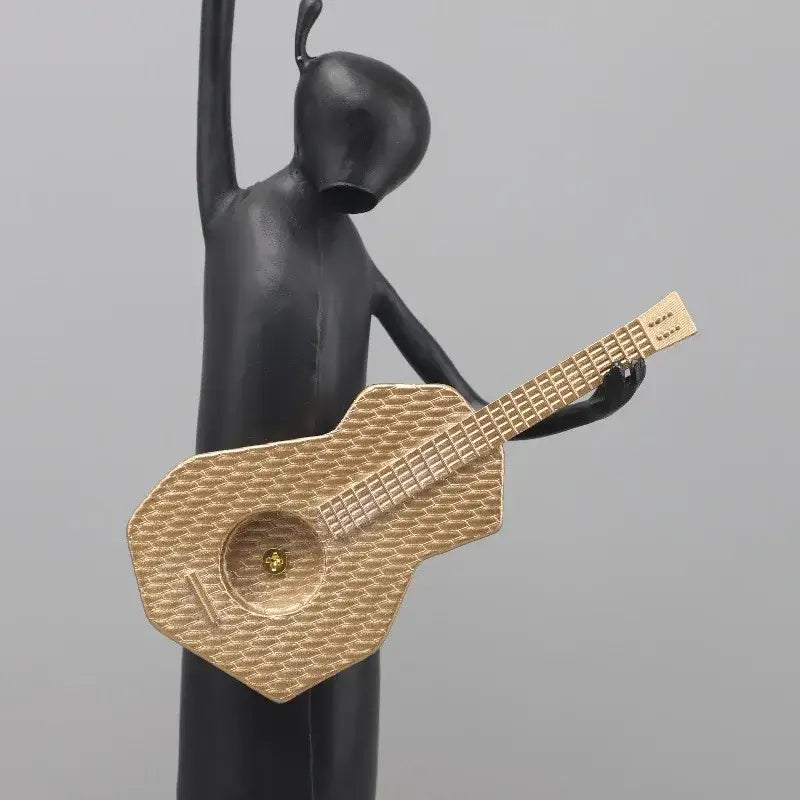 Abstract black and gold guitarist resin sculpture featuring a black figurine holding a textured gold guitar for living room decor