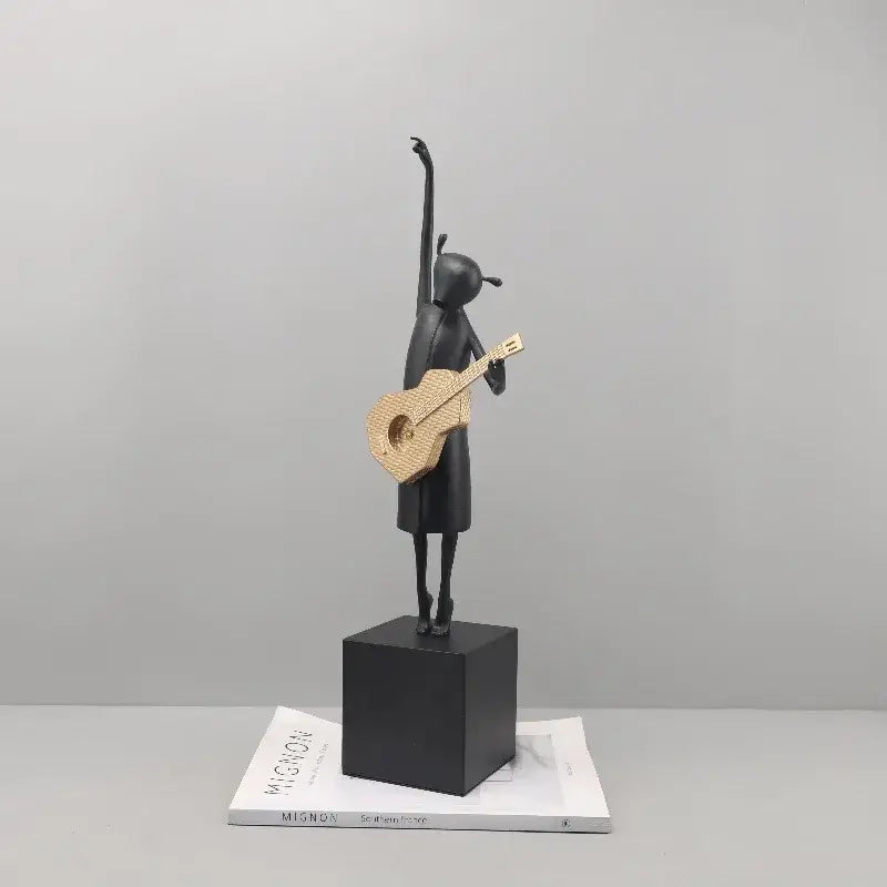 Abstract black and gold guitarist resin sculpture featuring a stylized girl figurine on a black cube base for decor